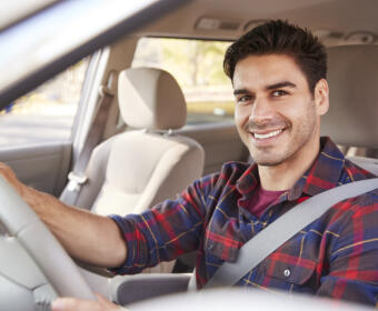 Young man in car driving seat looking to camera, portrait