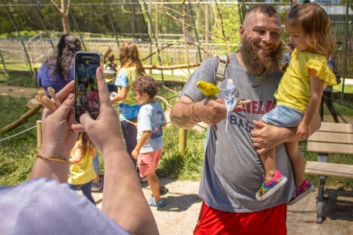 Man holding daughter feeding birds. 