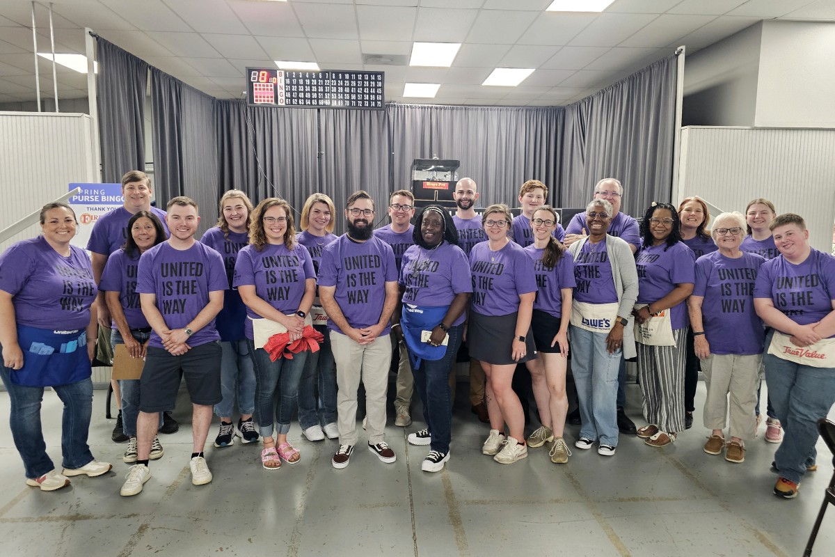 Group of people wearing purple shirts that read 'UNITED IS THE WAY' posing together in a bowling alley.
