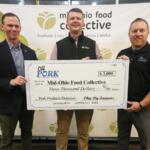 Three men hold a large ceremonial check for $3,000 to Mid-Ohio Food Collective, standing in front of a banner.
