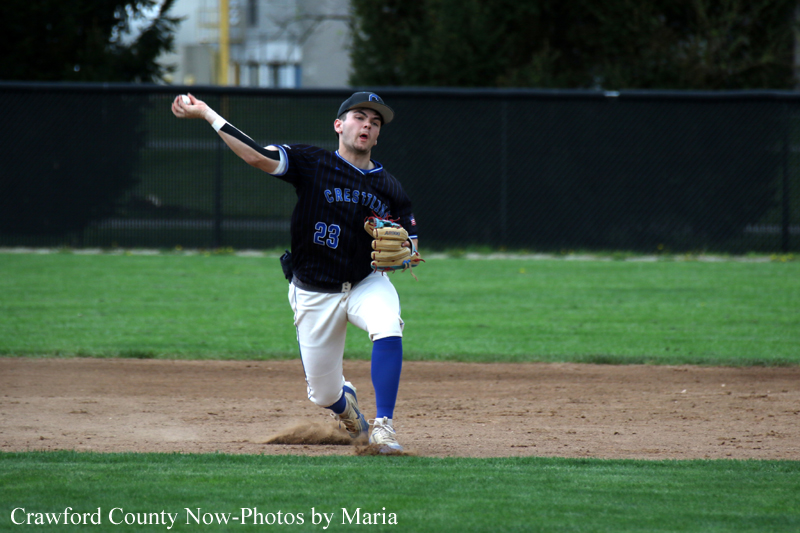 Baseball pitcher mid-throw on the infield, wearing a dark jersey with number 23 and blue socks.