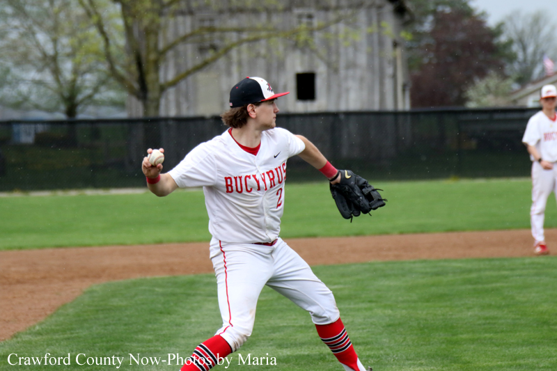 Baseball pitcher in a white red-uniform throws a pitch on a grassy field.