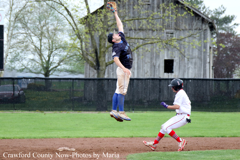 Baseball: a fielder in mid-air reaches with his glove to catch a ball near first base while a runner charges in from the right.