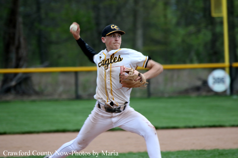 Baseball pitcher in a white-and-gold 'Eagles' uniform throws a pitch on the mound, glove on his left hand.
