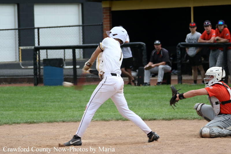 Baseball batter in white uniform swinging at a pitch as a catcher in orange gear crouches behind him on the dirt infield.