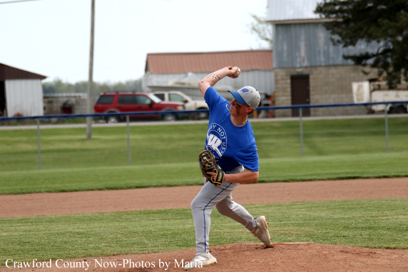 Young baseball pitcher in a blue jersey delivering a pitch on the baseball field