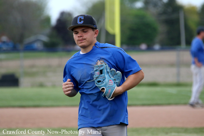 Baseball player in a blue jersey runs on the field with a glove in hand and a cap with a C on it.