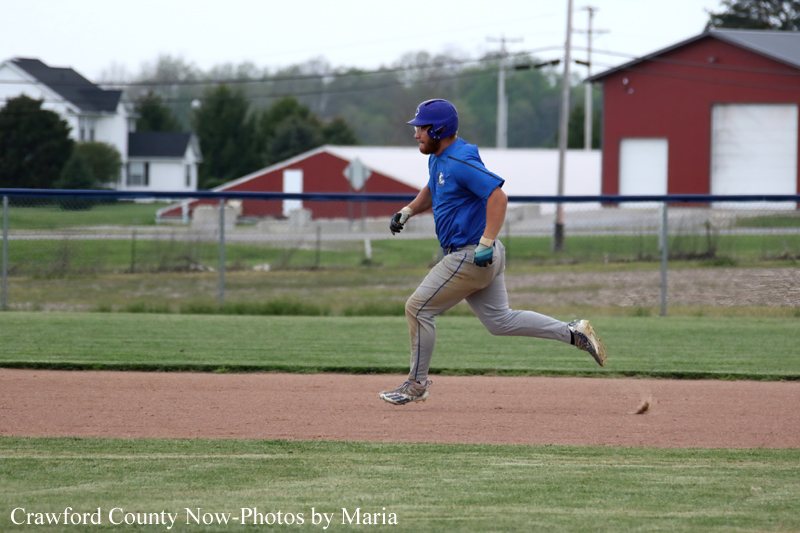 Baseball player in a blue uniform sprinting on the infield dirt during a game.