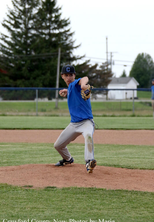 Baseball pitcher in a blue uniform on the mound winding up to throw a pitch.