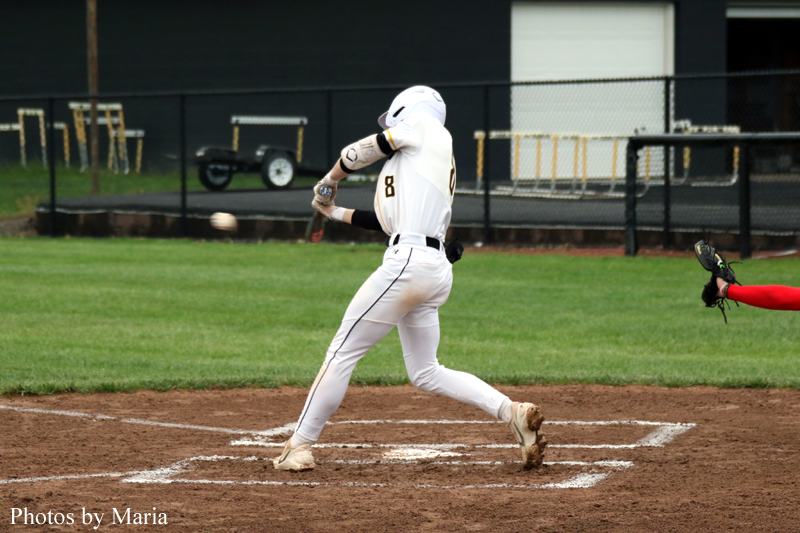 Baseball batter in a white uniform (number 8) swinging at a pitch near home plate on a dirt infield.