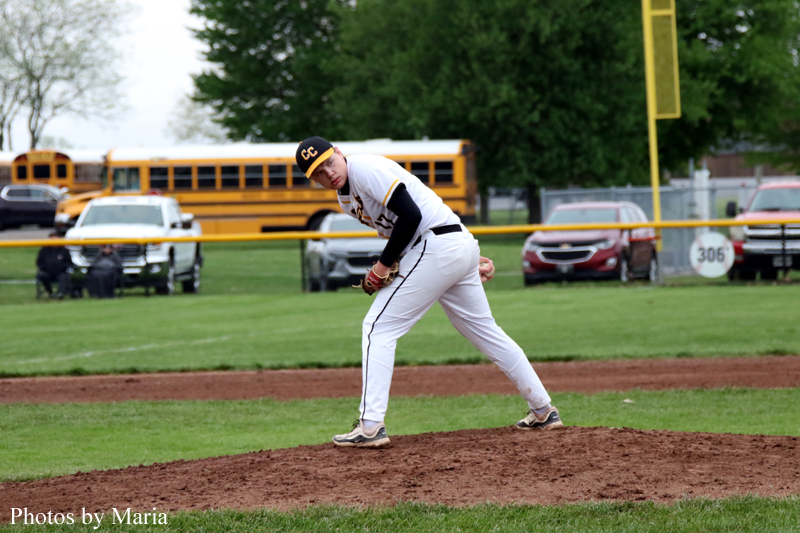 Baseball pitcher in a white uniform winding up on the pitcher's mound during a game.