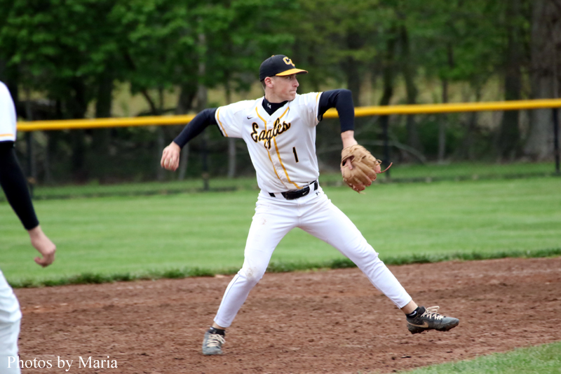 Baseball pitcher in a white and gold Eagles uniform mid-pitch onthe dirt mound with a glove on his left hand.