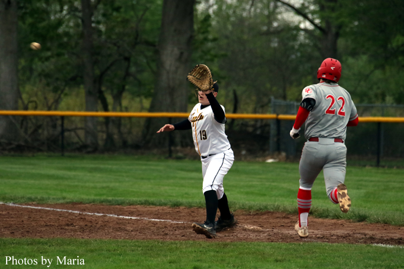 Baseball game: pitcher in white throws a ball as a baseman in gray jersey with #22 runs on the dirt infield.