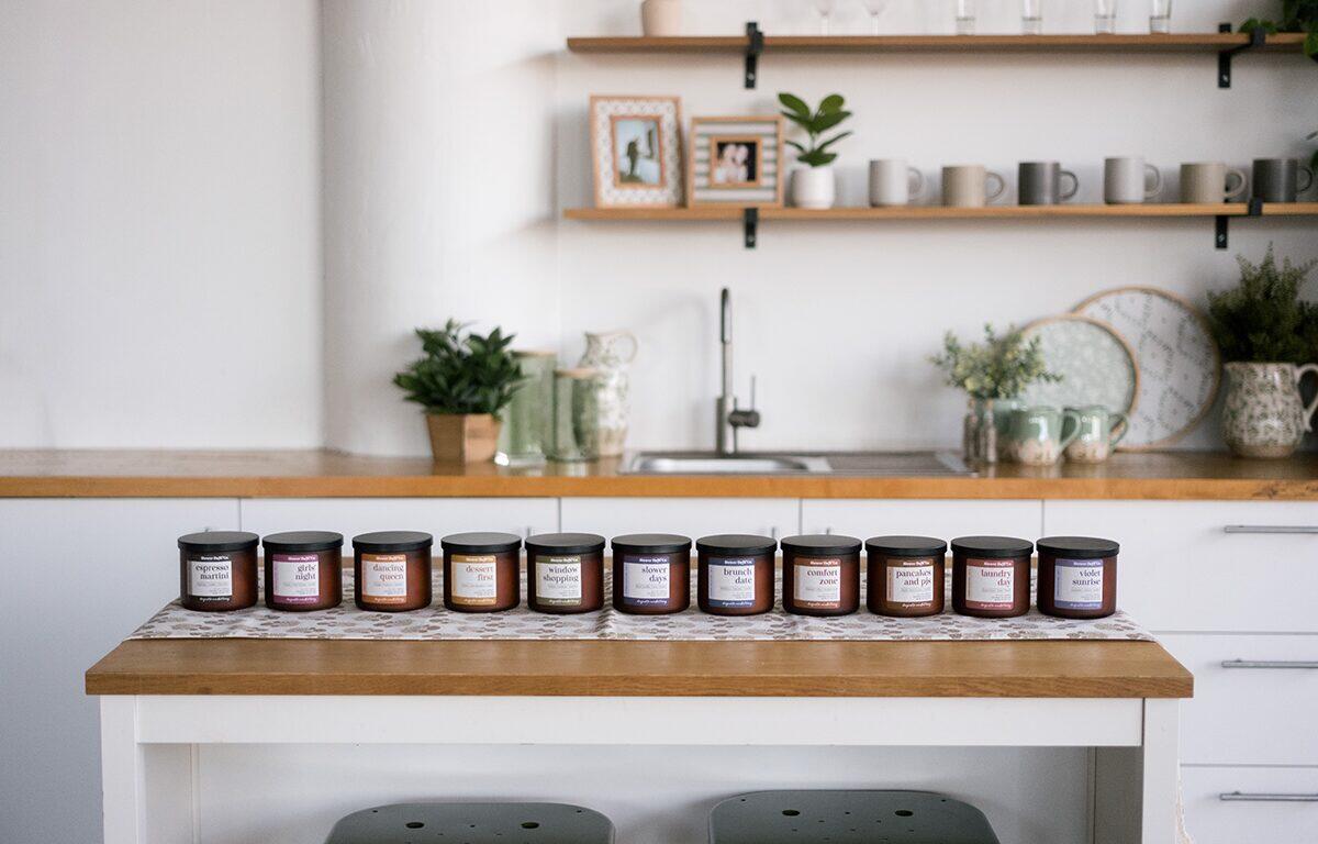 Row of small labeled jars on a wooden kitchen island in a bright, minimalist kitchen.