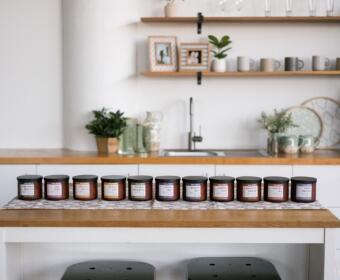 Row of small labeled jars on a wooden kitchen island in a bright, minimalist kitchen.