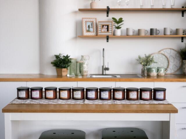Row of small labeled jars on a wooden kitchen island in a bright, minimalist kitchen.