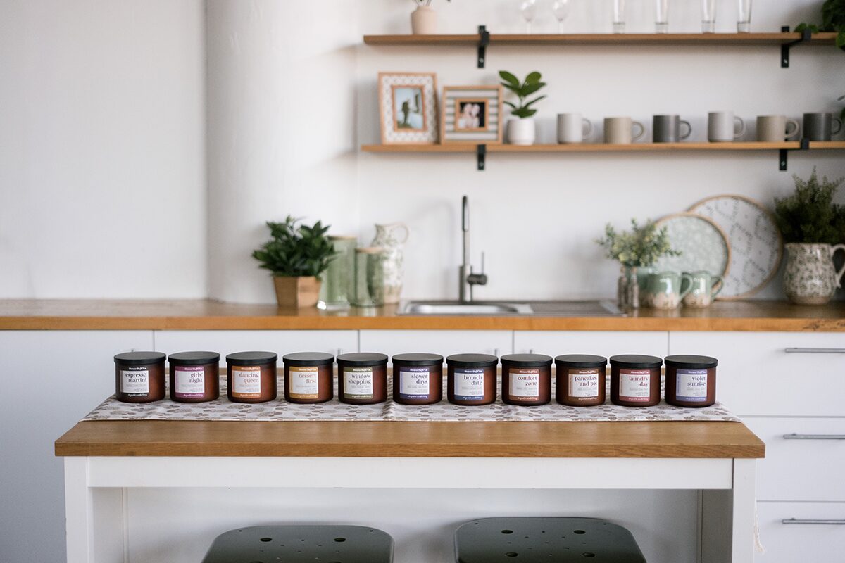 Row of small labeled jars on a wooden kitchen island in a bright, minimalist kitchen.
