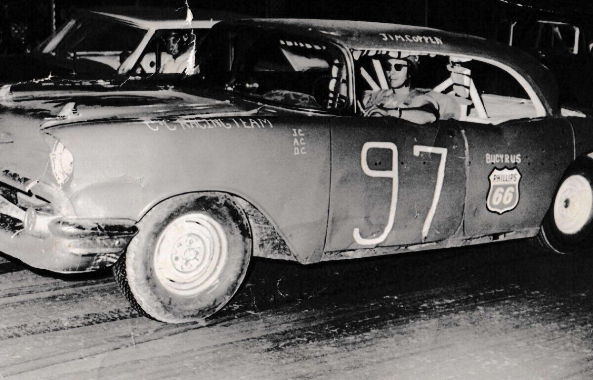 Vintage stock car 97 with Philips 66 logo, driver in helmet in the cockpit after a crash.