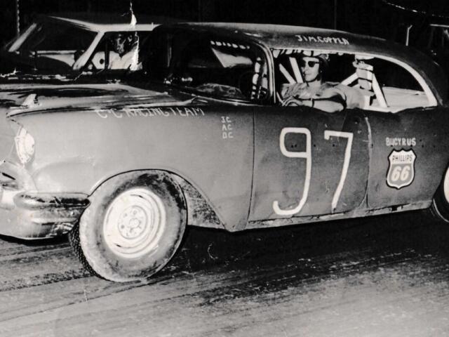 Vintage stock car 97 with Philips 66 logo, driver in helmet in the cockpit after a crash.