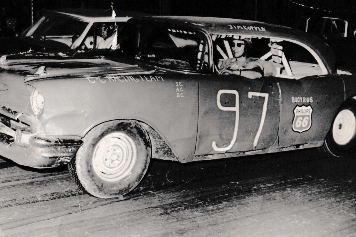 Vintage stock car 97 with Philips 66 logo, driver in helmet in the cockpit after a crash.