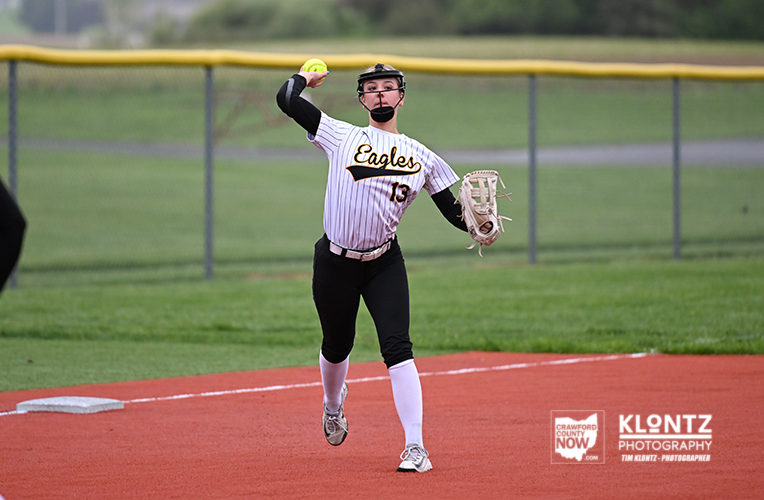 Softball pitcher in an Eagles uniform winds up to throw on a dirt mound, numbered 13.