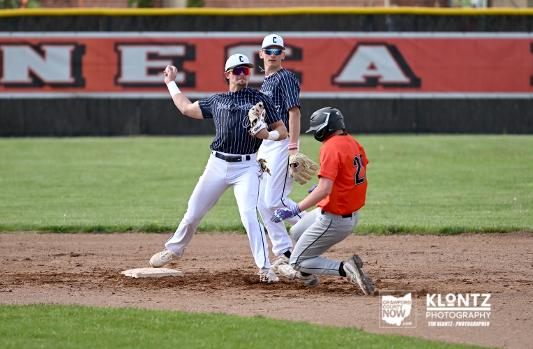 Baseball play at second base: runner slides as fielder leans into the bag while a baserunner advances and a fielder covers second.