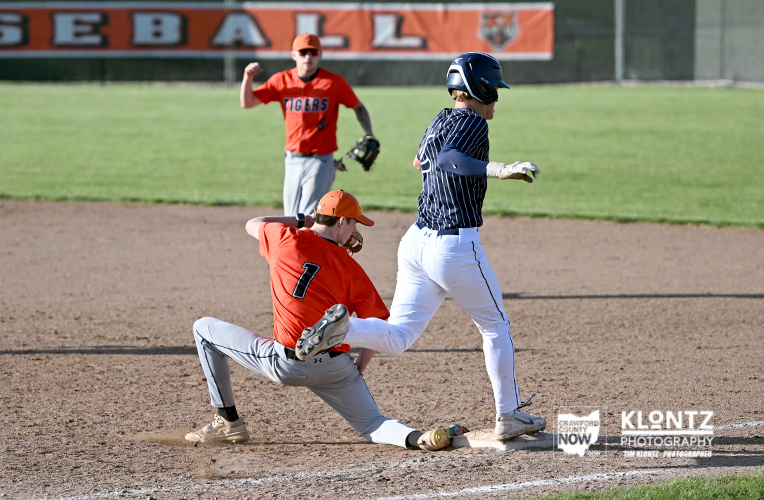 Baseball play: a baserunner in a dark pinstripe uniform slides into a bag while a fielder in orange reaches to tag him.