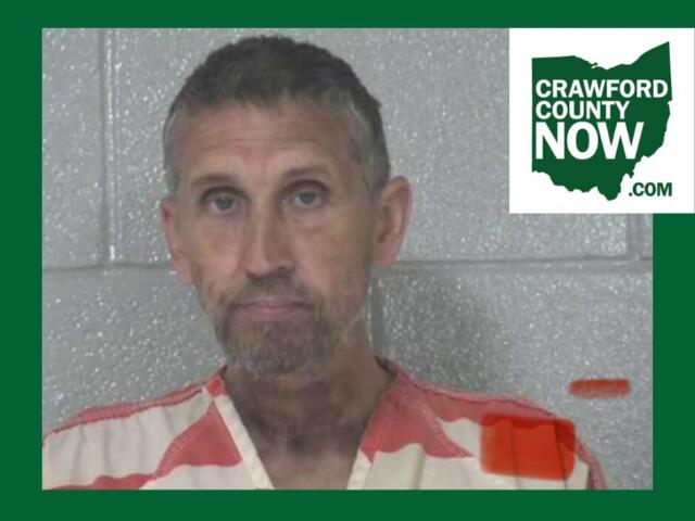 Mugshot of a man with short gray hair in an orange-striped jail uniform, posed against a gray cinder-block wall; Crawford County Now logo in the corner.