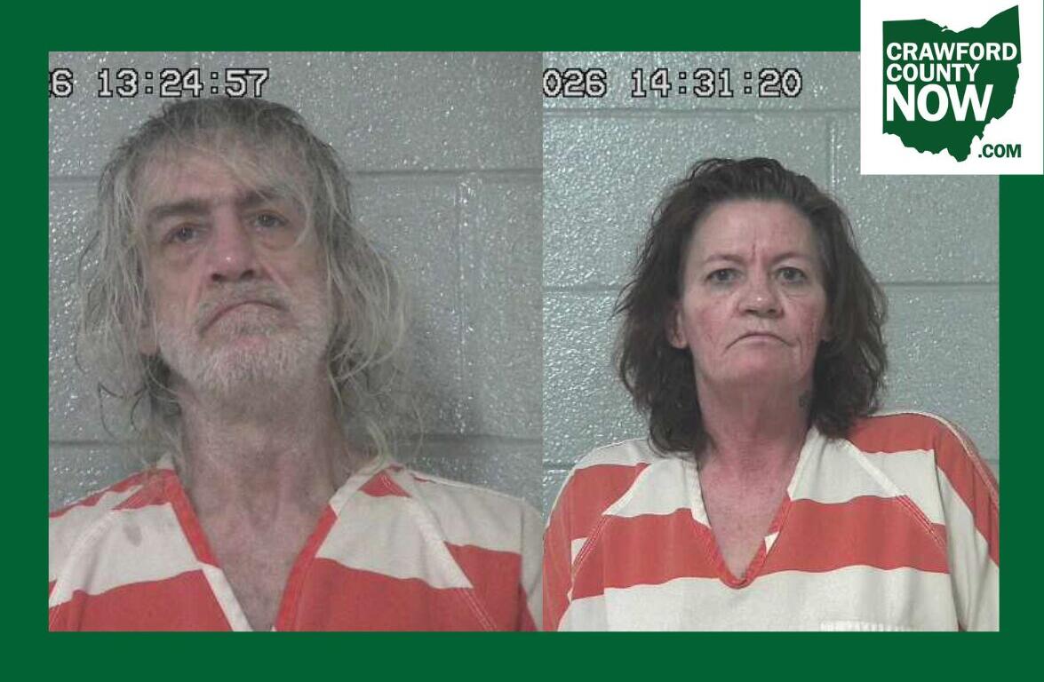 Two side-by-side mugshots: man with long gray hair and beard on the left, woman with dark hair on the right, both in orange-and-white striped jail uniforms against a gray cinder-block wall; timestamp overlays and Crawford County Now logo in corner.