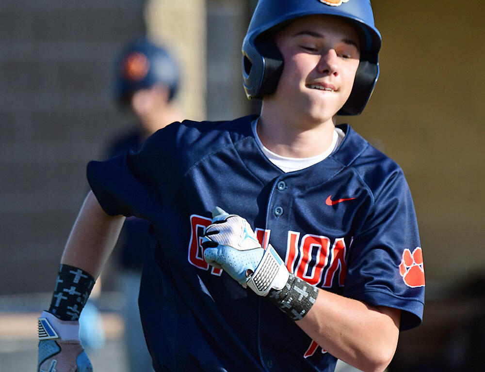 Young baseball player in a navy uniform sprinting during a game, helmet on and glove ready.
