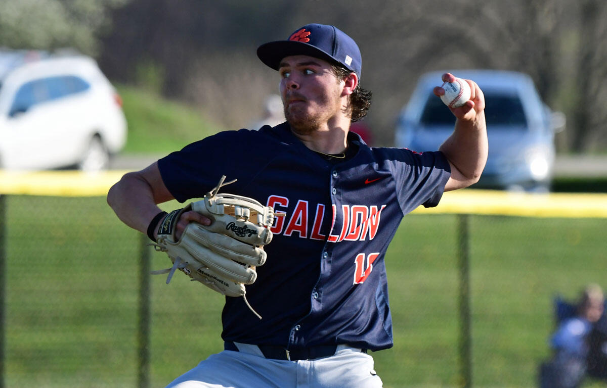 Right-handed baseball pitcher in a navy uniform with 'GALLION' lettering, mid-throw on a sunny field.