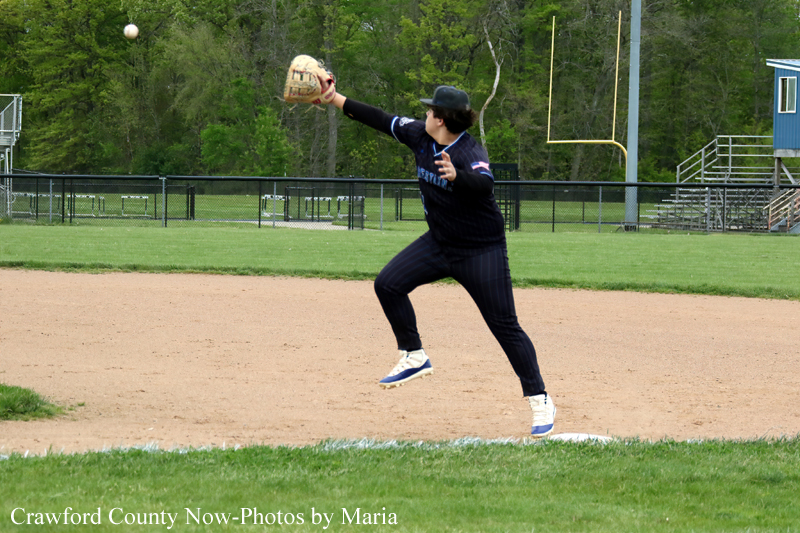 Baseball pitcher in a dark uniform on the mound, glove up, throwing a pitch on a dirt infield.