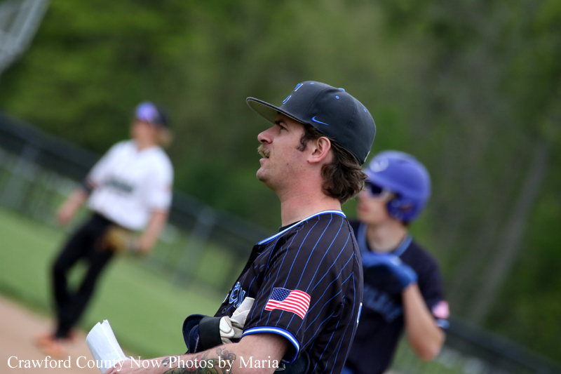 Baseball player in a black pinstripe jersey with an American flag patch on the sleeve, standing on the field.