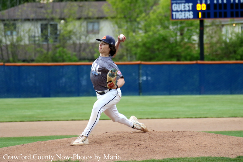 Right-handed baseball pitcher delivering a throw on the mound during a game, with a scoreboard and outfield fence in the background.