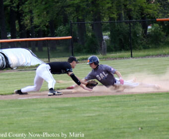 Baseball play: a runner slides into a base as a defender dives to tag him, dust kicking up on the infield.