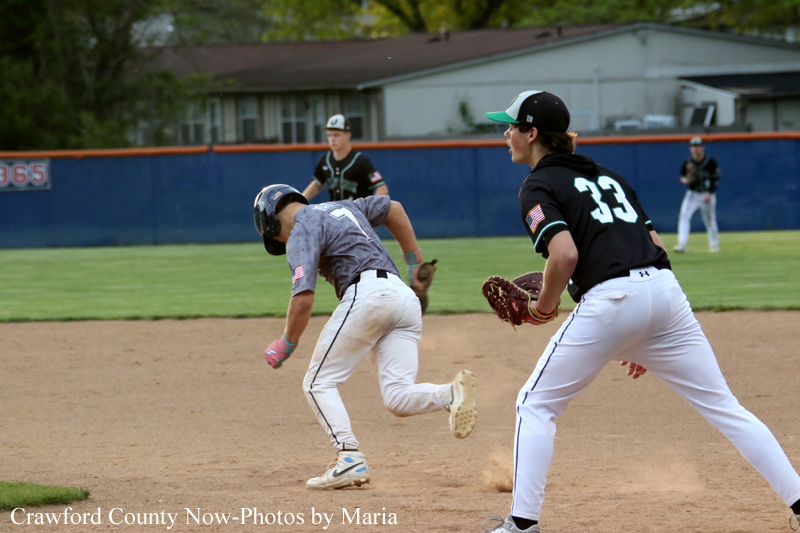 Baseball game: a baserunner in gray slides toward first as a fielder in black with number 33 moves to field the ball.