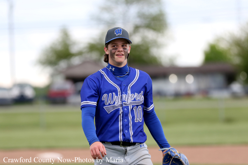 Baseball player in a blue uniform with number 10 smiles on the field.