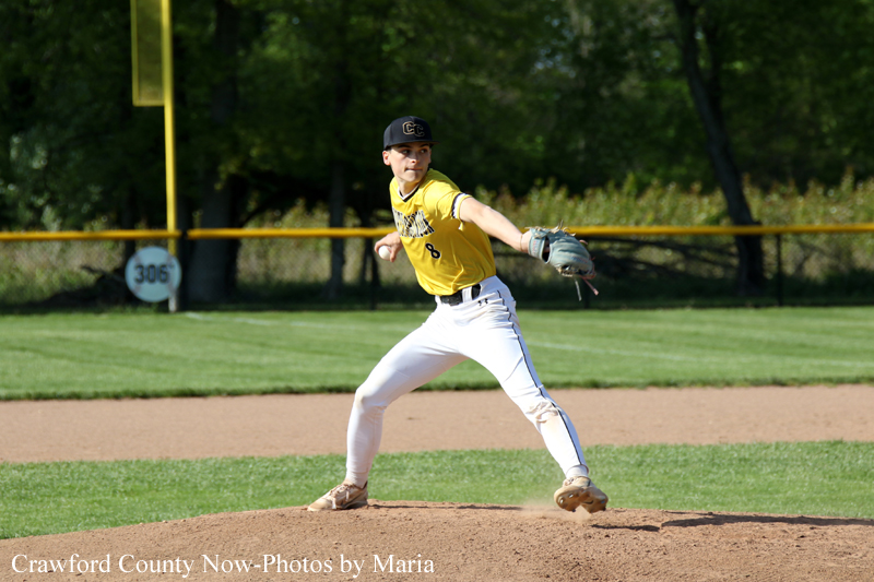 Baseball pitcher in a yellow uniform winds up on the mound, glove in left hand, ready to throw.