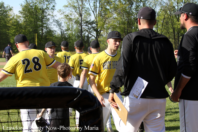 Baseball players in yellow jerseys shake hands with coaches on a sunny field after a game or practice.