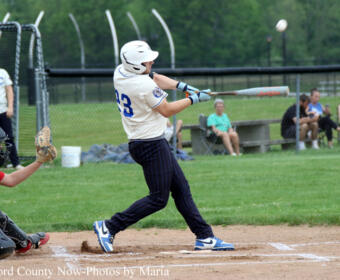 Baseball batter in white jersey #23 swings at a pitch as the catcher crouches behind home plate.