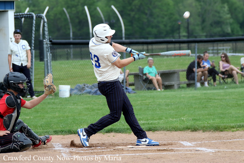 Baseball batter in white jersey #23 swings at a pitch as the catcher crouches behind home plate.