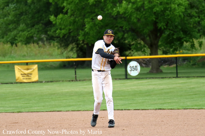 Baseball player in white and yellow uniform on the infield, ball midair as he prepares to throw or field.