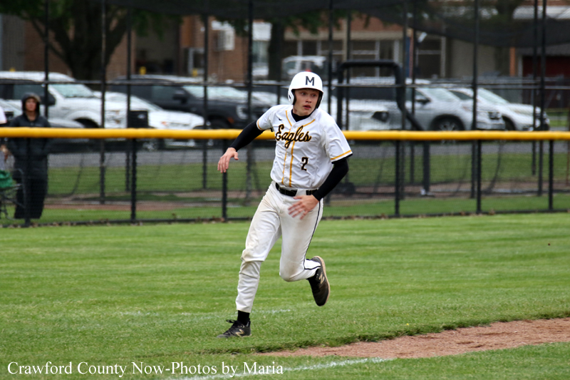 Young baseball player in a white Eagles uniform runs on the grassy field, helmet on, during a game.