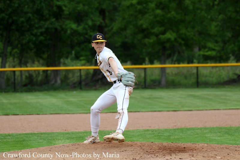 Baseball pitcher in a white uniform with CC on the cap, mid-pitch on the mound with green outfield behind him.