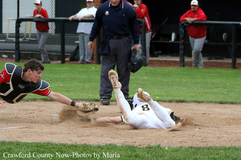 Baserunner slides into a bag as a fielder dives to tag him, dust puffing up on the dirt infield.