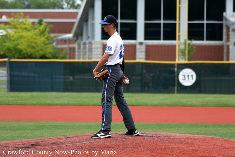 Baseball pitcher on the mound in a white uniform, preparing to throw during a game.