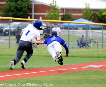 Baseball game action: blue baserunner slides into a base as the white-uniformed fielder reaches to tag him.