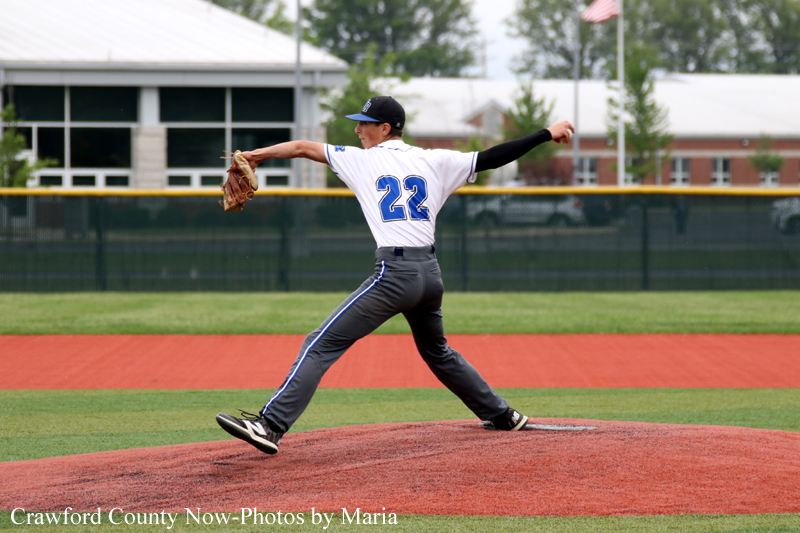 Baseball pitcher in white jersey number 22 delivering a pitch from the mound on a sunny field.
