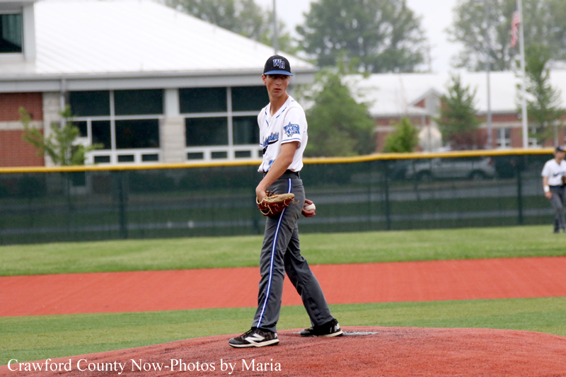 Baseball pitcher in white jersey and gray pants stands on the pitcher's mound during a game.