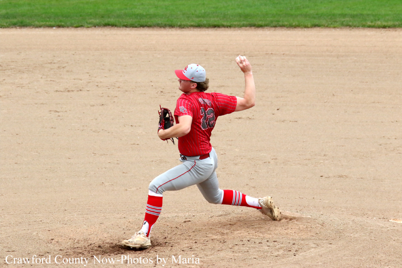 Baseball pitcher in a red uniform throwing a pitch on the dirt field